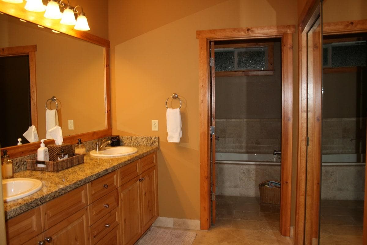 Master bath with 2 sinks and limestone flooring.